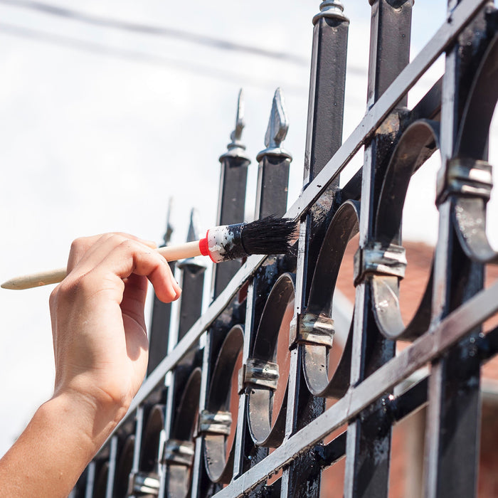 brushing paint onto metal gate